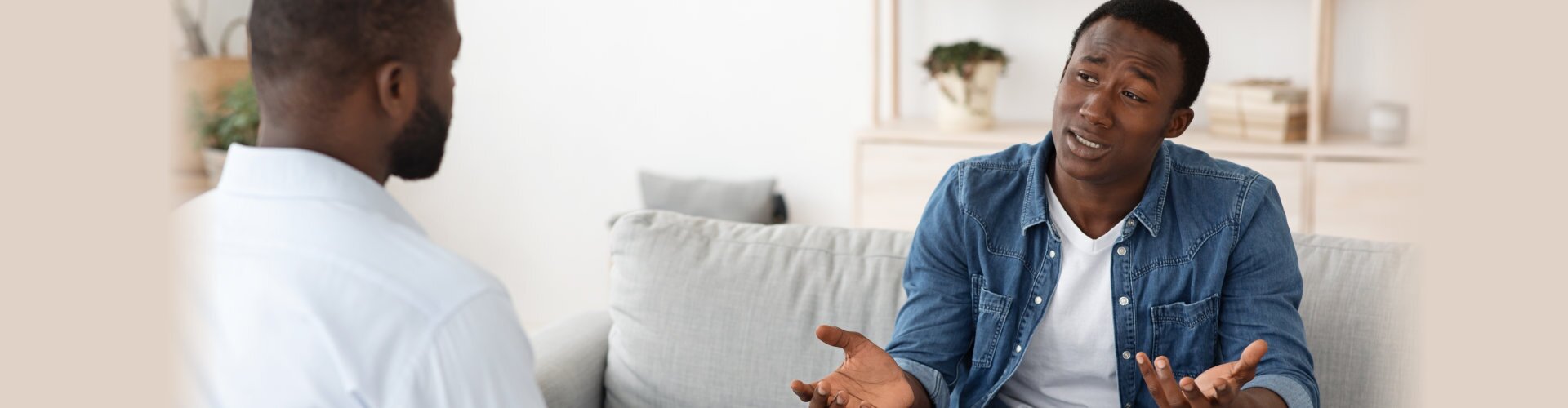 stressed african man explaining his problems to psychologist at individual therapy session