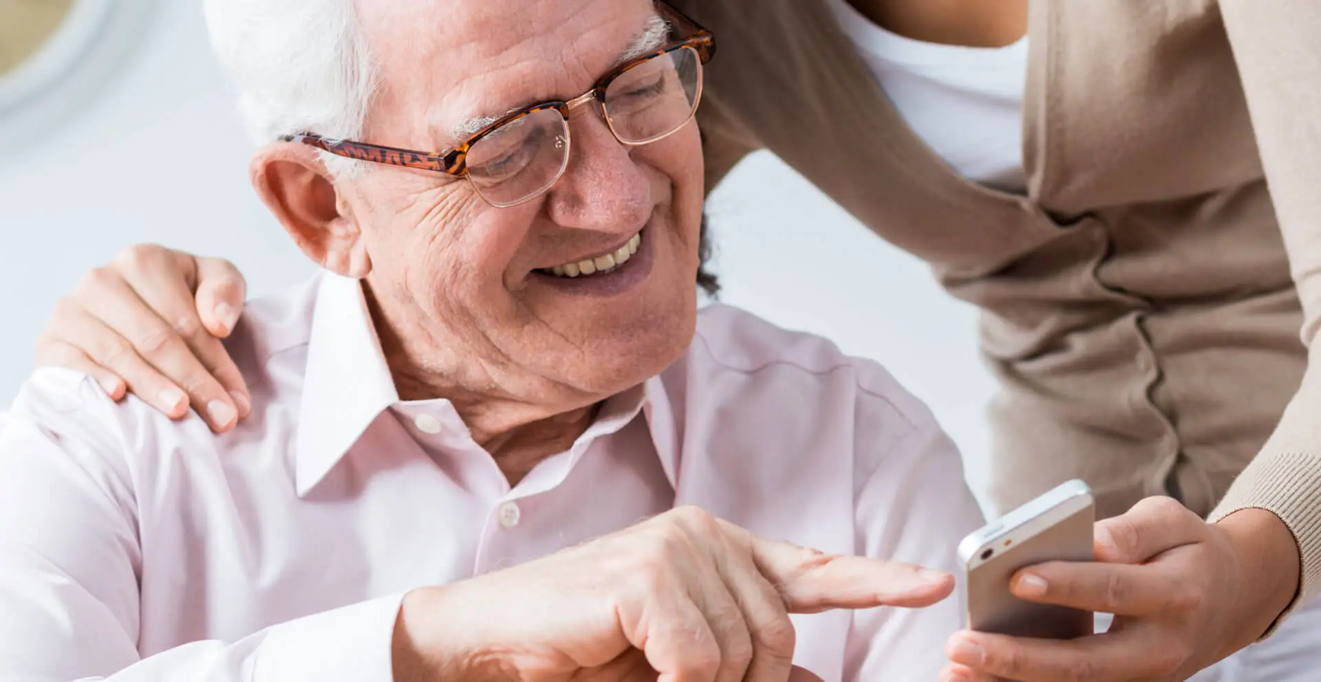 caregiver helping an old man with modern technology