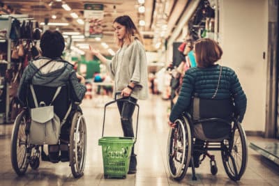 young girl helping two disabled women in wheelchair in a department store